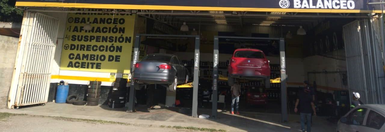 Autos en elevadores dentro del taller de Nego Llantas